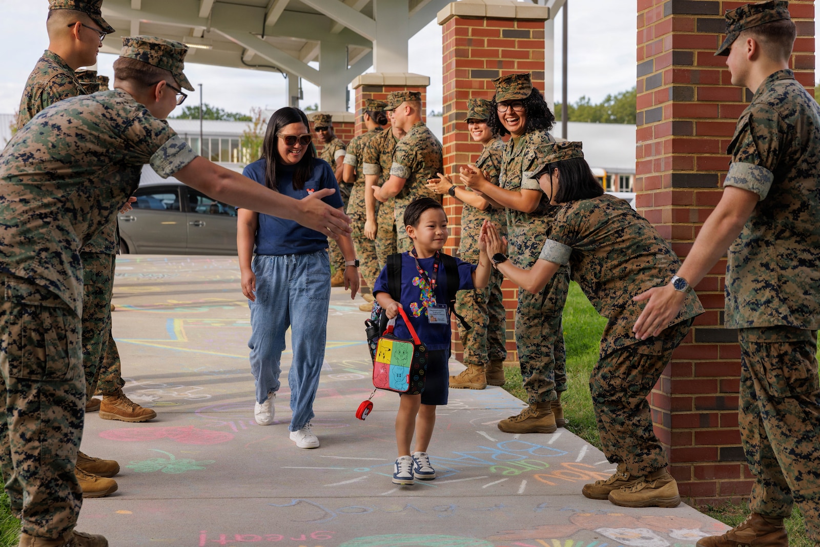 U.S. Marines with Marine Corps Base Quantico welcome a student to their first day of school during a back-to-school celebration at the Crossroads Elementary School on Marine Corps Base Quantico, Virginia, Aug. 17, 2026. This event welcomed students back to the classrooms, strengthening the bonds between the Marines and the MCB Quantico community. (U.S. Marine Corps photo by Lance Cpl. Federico Marquez)