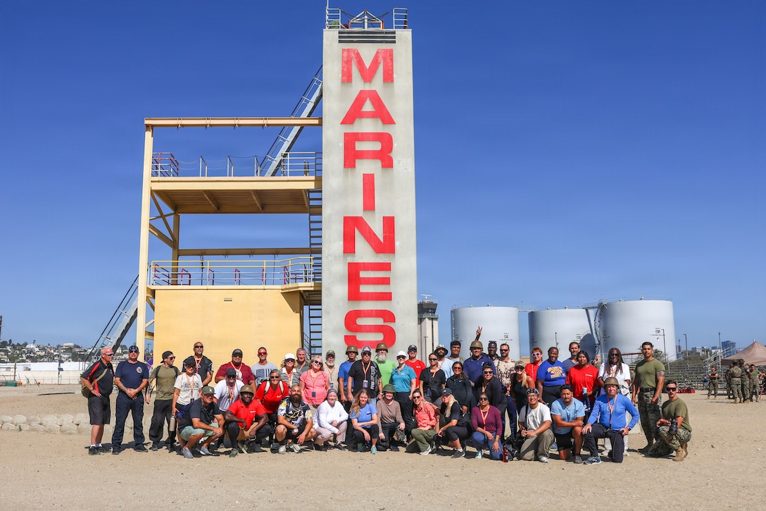 U.S. Marines and educators with 12th Marine Corps District pose for a photograph next to a rappel tower during an Educators Workshop event at Marine Corps Recruit Depot San Diego in San Diego, California, July 29, 2026. The Educators Workshop program provides selected educators and influential community members with an experiential opportunity to see how the Marine Corps transforms young men and women into Marines. The workshop also provides attendees with current information regarding Marine Corps training practices, military job skills, service opportunities, military lifestyle, and educational benefits available to Marines. (U.S. Marine Corps photo by Lance Cpl. Monserrath Mora)