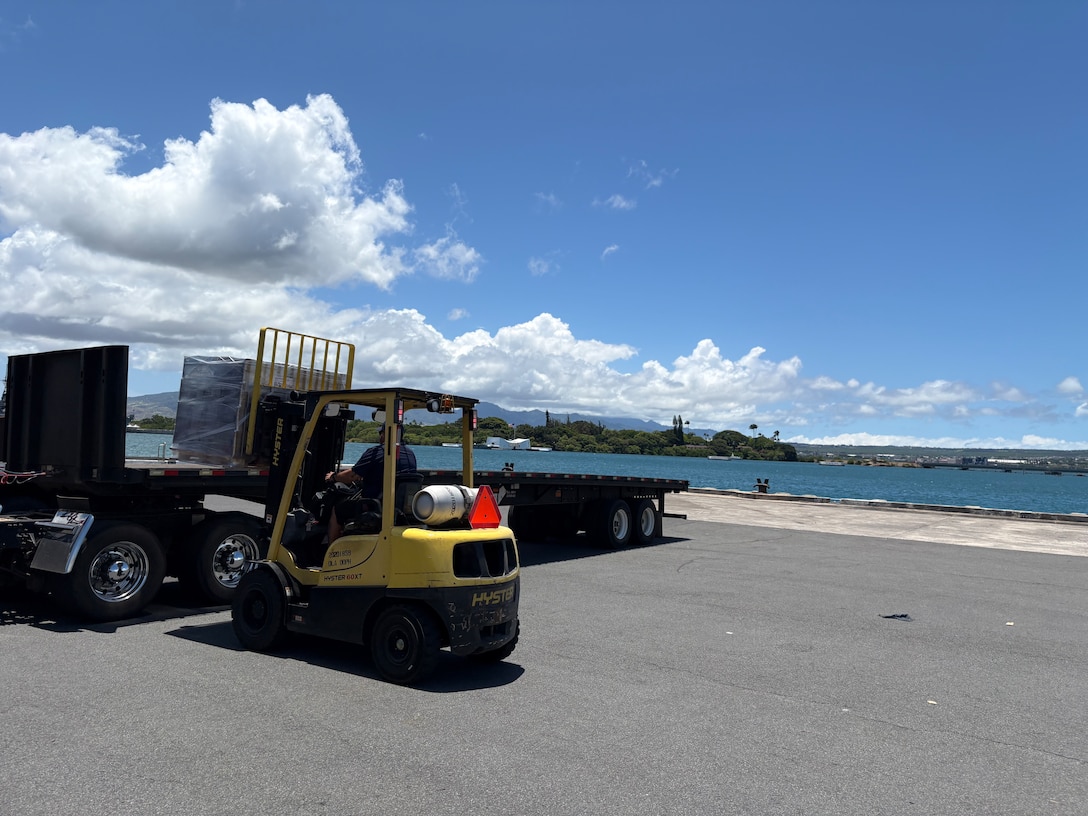 A forklift loading items onto a flatbed truck.
