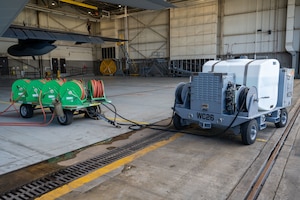 An Airman-designed aircraft engine compressor wash cart is connected to an AC-130J Ghostrider