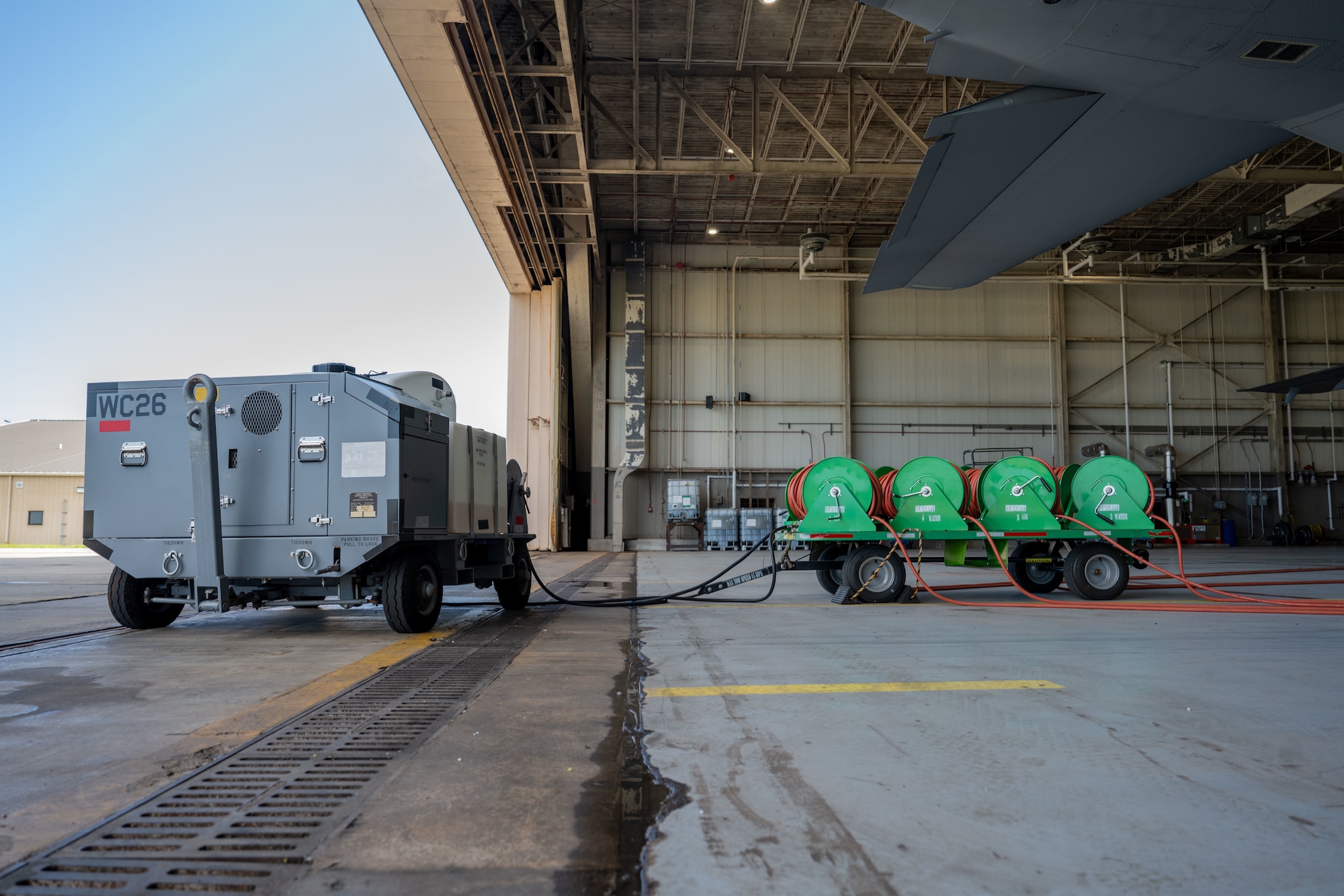 An Airman-designed aircraft engine compressor wash cart is connected to an AC-130J Ghostrider
