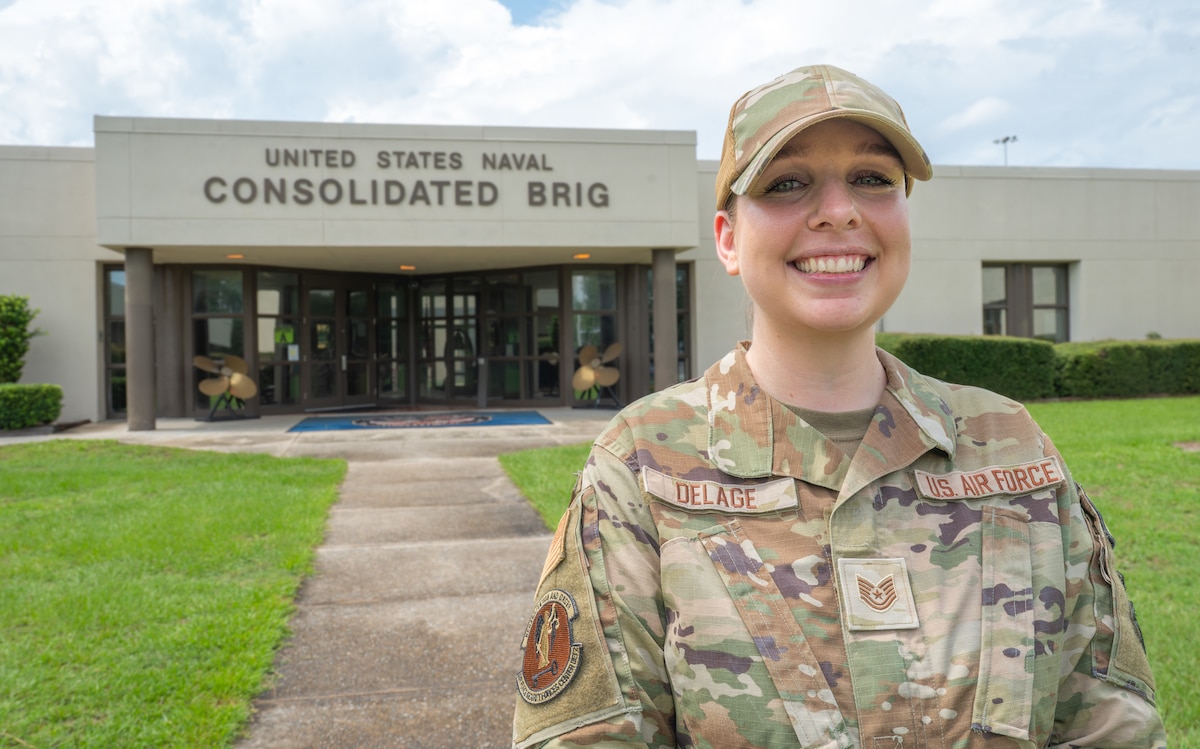 A female Airman stands in from of a building
