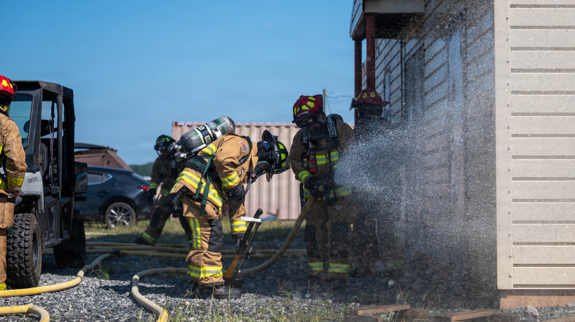 firefighters suppress a simulated house fire