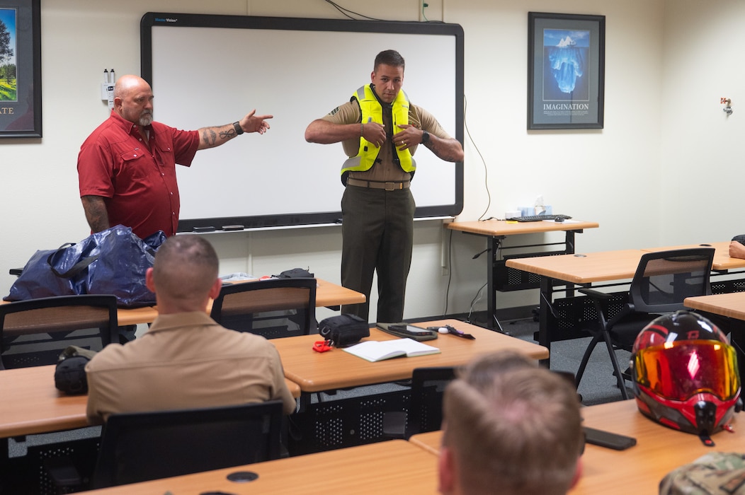 Mark Dumdie, 17th Training Wing Safety motorcycle safety program manager, and U.S. Marine Corps Sgt. Alejandro Clausell, Marine Detachment Goodfellow motorcycle mentorship program president, showcase the different protected areas of an airbag vest during a motorcycle safety meeting at Goodfellow Air Force Base, Texas, Aug. 14, 2026. The vest is designed to protect multiple vital parts of the upper back, lower back, chest and neck regions of a motorcyclist in the event of a mishap. (U.S. Air Force photo by Senior Airman Brian Lummus)