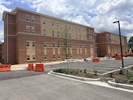 Exterior of two 4-story buildings and an empty parking lot with construction barricades.
