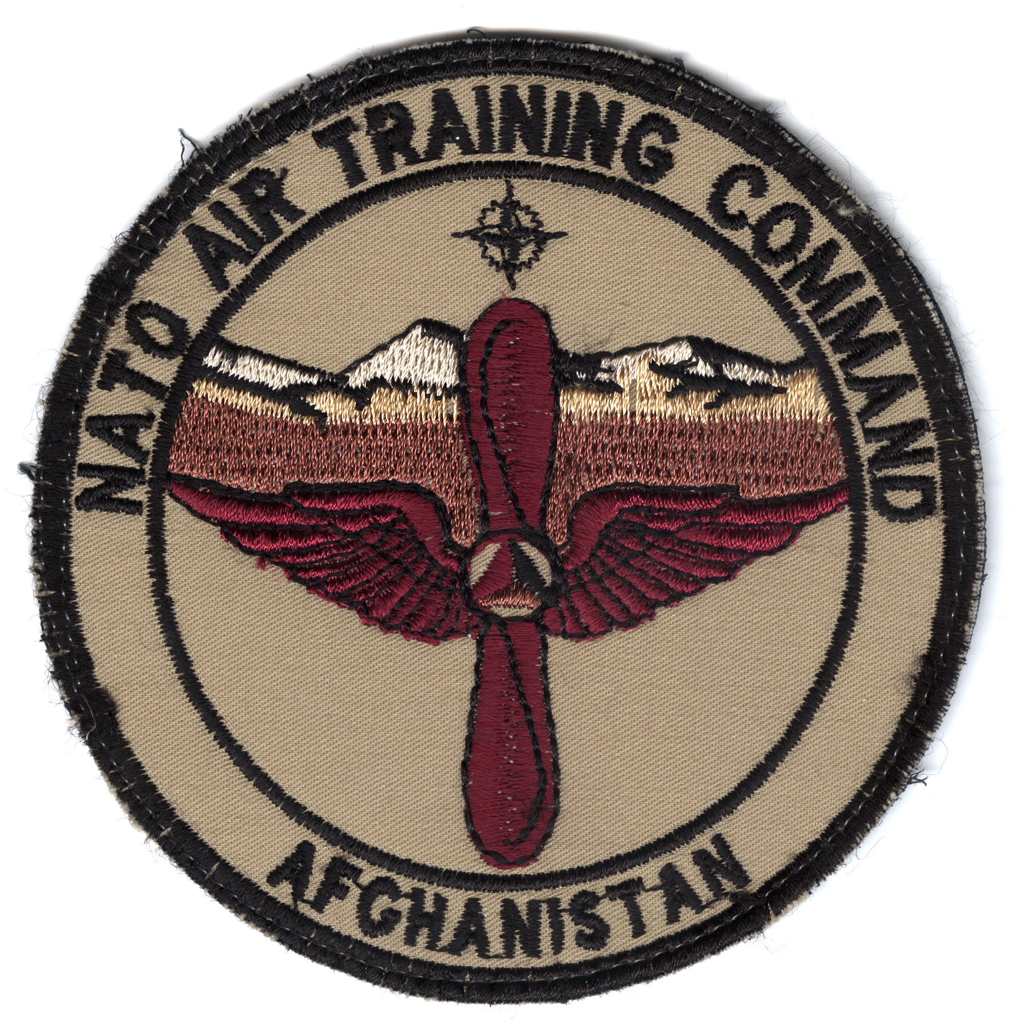 Patch worn by NATO Air Training Command (NATC-A) Airmen in Afghanistan, 2010-2015. The traditional propeller-and-wings training symbol features the Afghan Air Force emblem in the center. The background includes the NATO symbol and Afghanistan’s central plains and Hindu Kush mountains. Before NATC-A, the mission was called Combined Air Power Transition Force, or CAPTF.