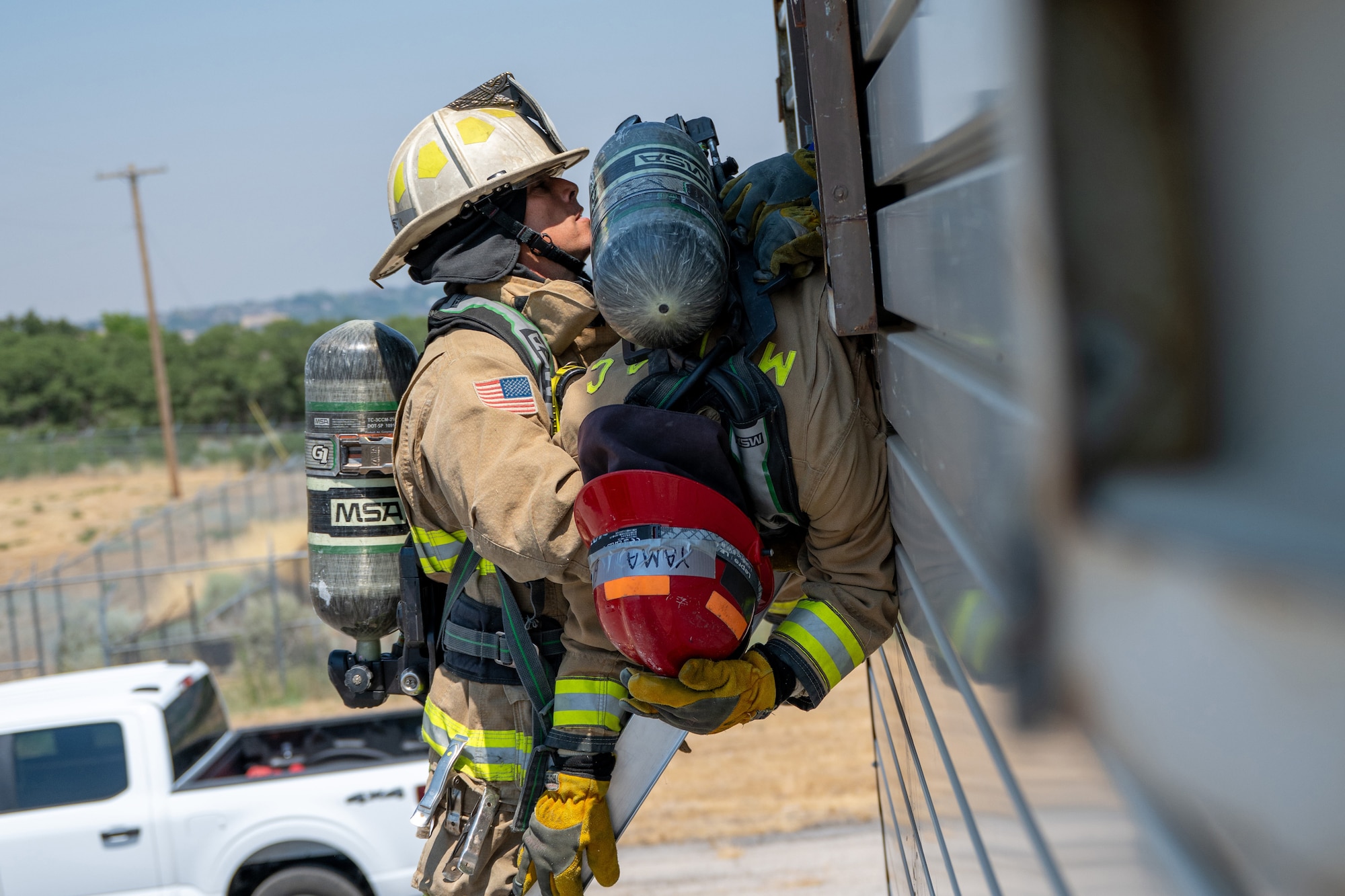 A firefighter on a ladder holds another firefighter that was bailed out of a window