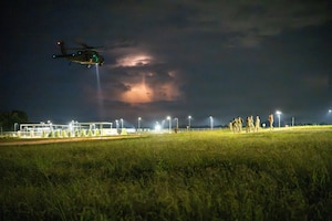 A UH-60 Black Hawk helicopter flying at night.