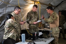 Airmen review financial paperwork inside a deployment tent during an exercise.