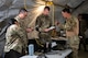 Airmen review financial paperwork inside a deployment tent during an exercise.