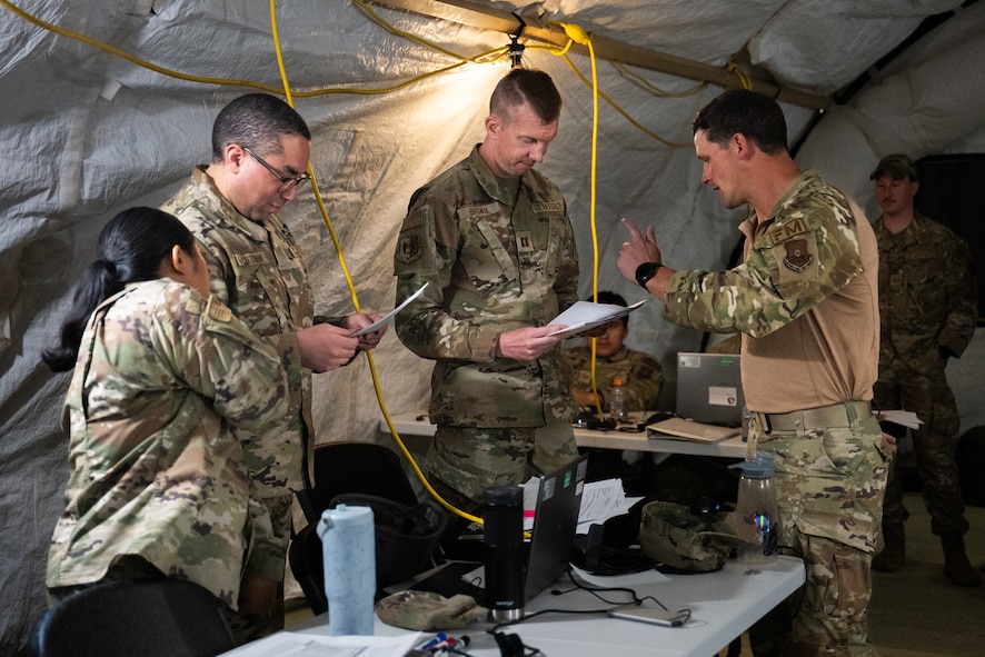 Airmen review financial paperwork inside a deployment tent during an exercise.