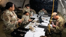 5th Comptroller Squadron Airmen review financial paperwork inside a deployment tent during an exercise.