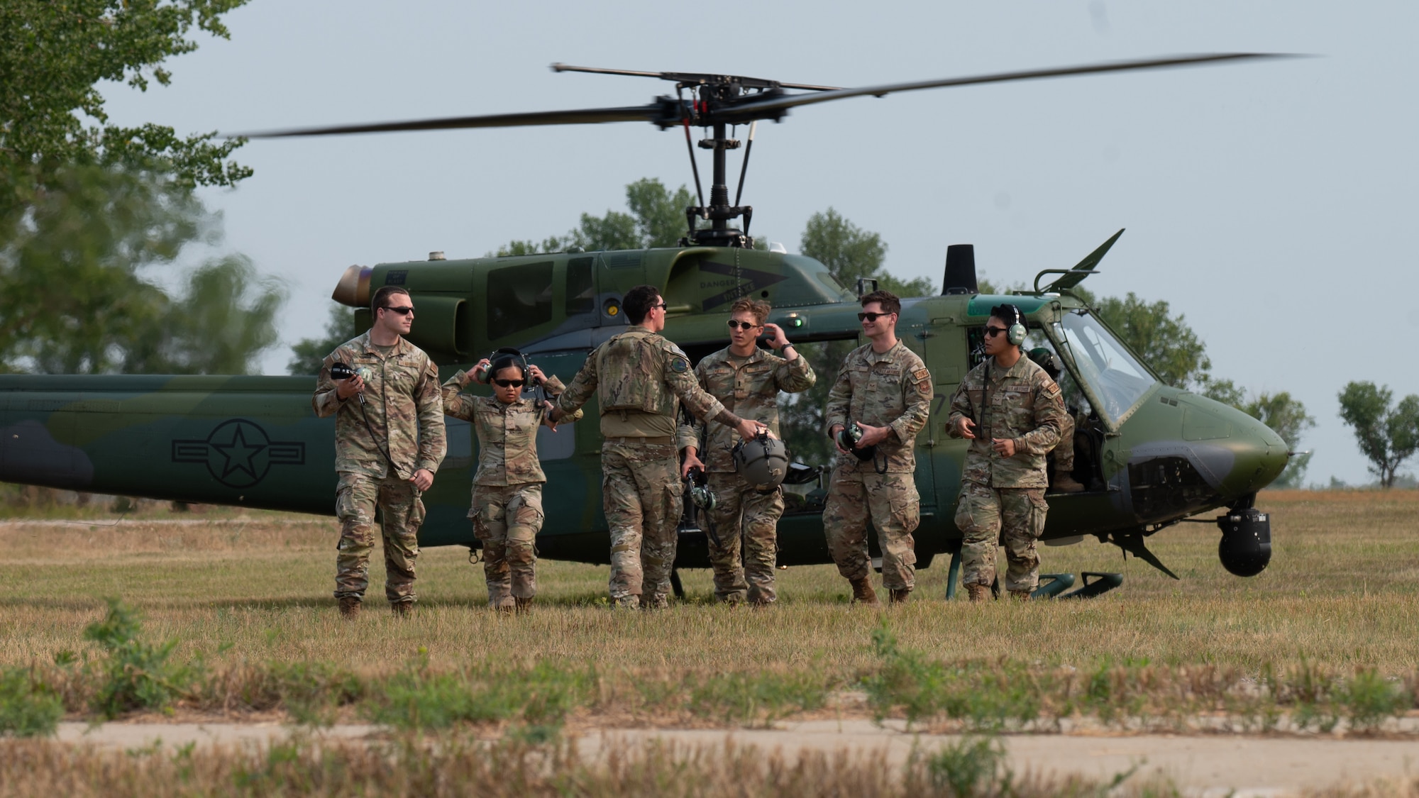 Airmen walk away from a helicopter.