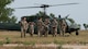 Airmen walk away from a helicopter.