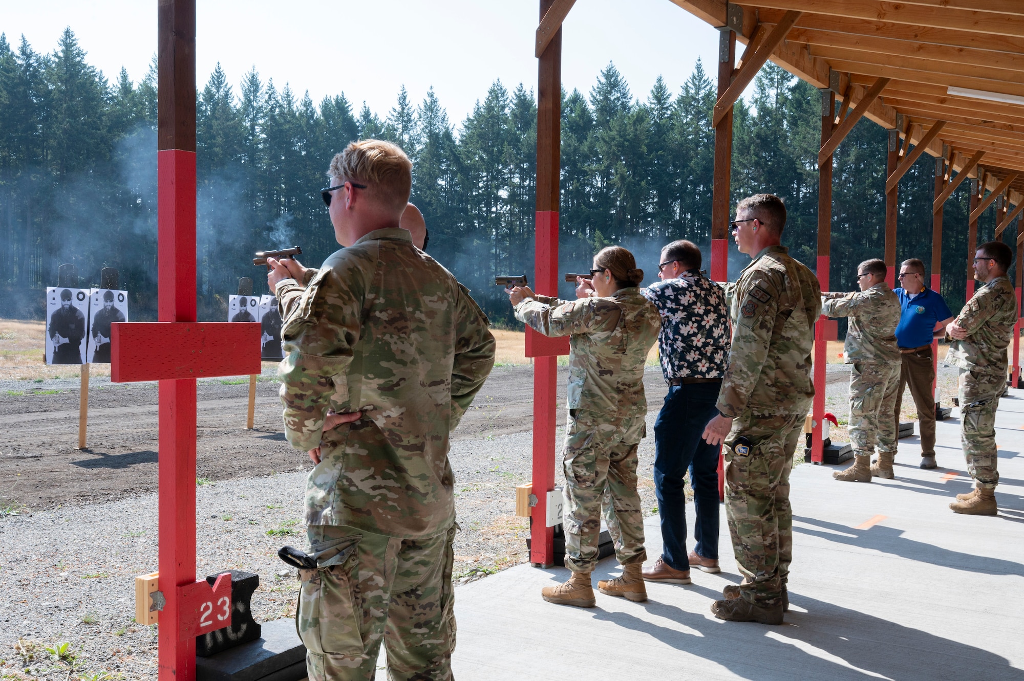 A group of lined-up people shoot weapons at a shooting range.