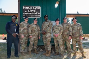 A group of service members stand in front of a plaque for a picture.
