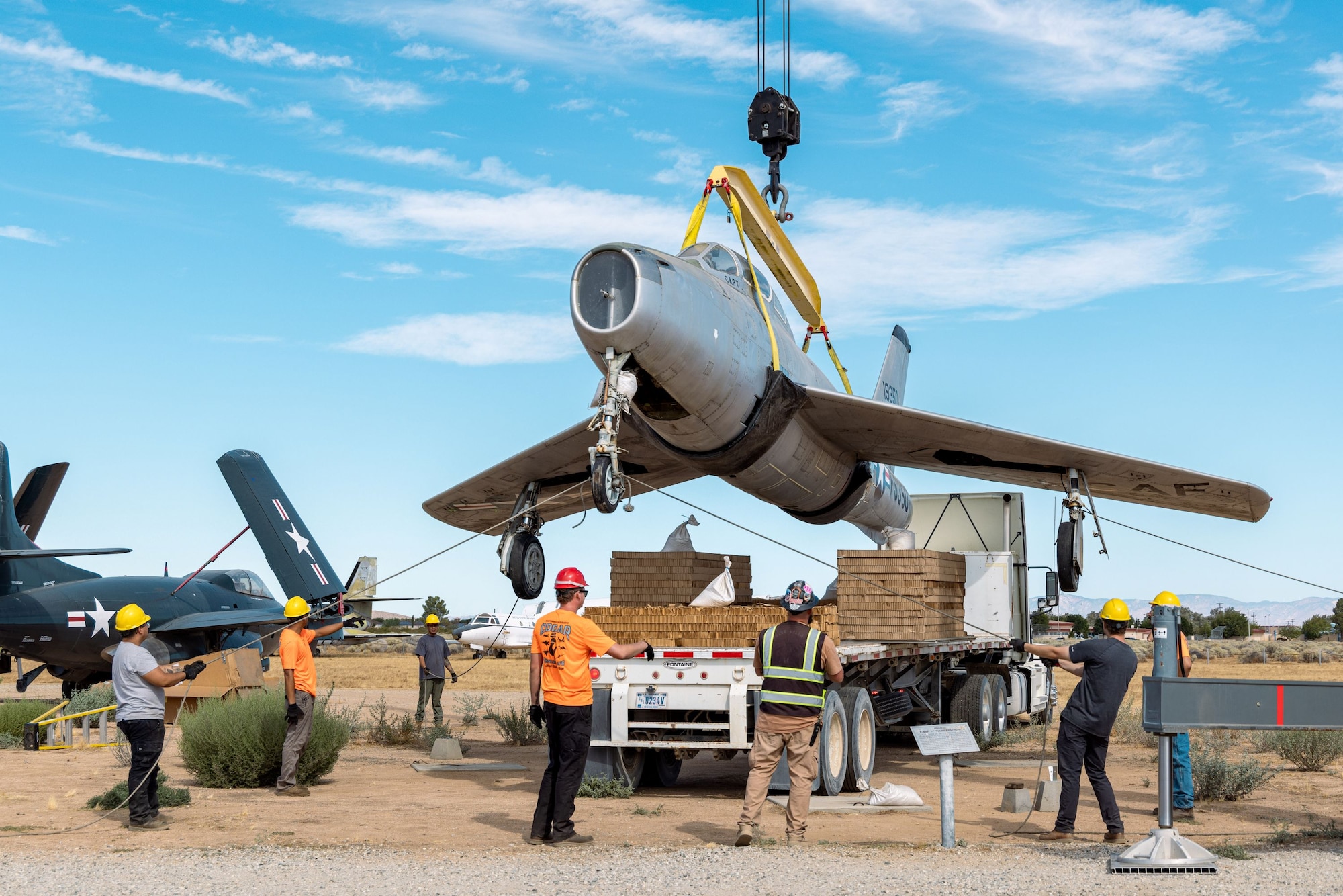 Members of the 412th Civil Engineer Squadron and the Crashed, Damaged, and Disabled Aircraft Recovery team used a 55-ton crane to hoist the F-84F Thunderstreak tail number 51-9350 onto a specially modified tractor-trailer at Edwards Air Force Base, California, Aug. 14. The aircraft was relocated to the base's south gate as part of a collaborative initiative to bring aviation history to the installation entry points. (U.S. Air Force photo by Ariana Ortega)