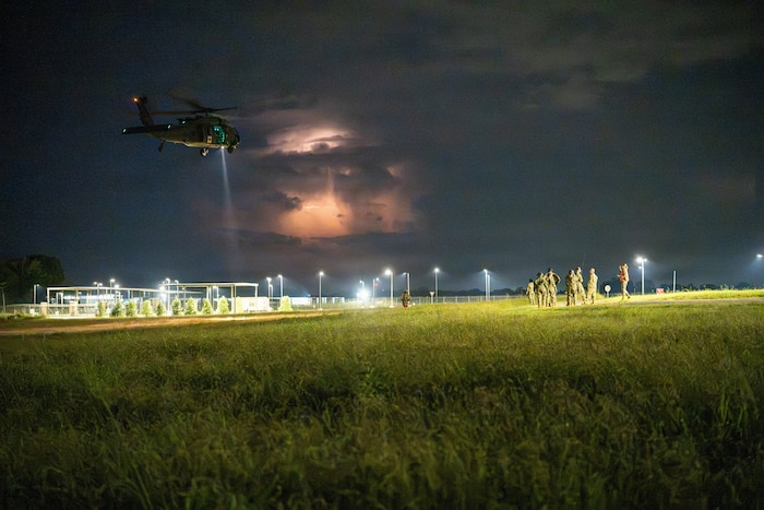 A UH-60 Black Hawk helicopter flying at night.