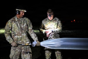 U.S. Army Sgt. Eric Atwater, left, and Sgt. Keaton Thompson, right, assigned to Multi-Domain Command-Europe inflate a high-altitude balloon during nighttime operations in Powidz, Poland, Jul. 28, 2026. The Soldiers prepared the balloon and its payload for launch in support of multidomain experimentation and capability development. (U.S. Army photo by Sgt. 1st Class Rajheem Dixon)