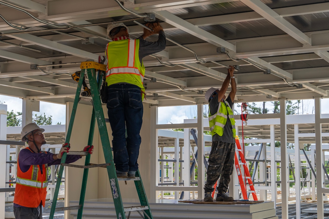 Construction workers assemble a steel building structure.