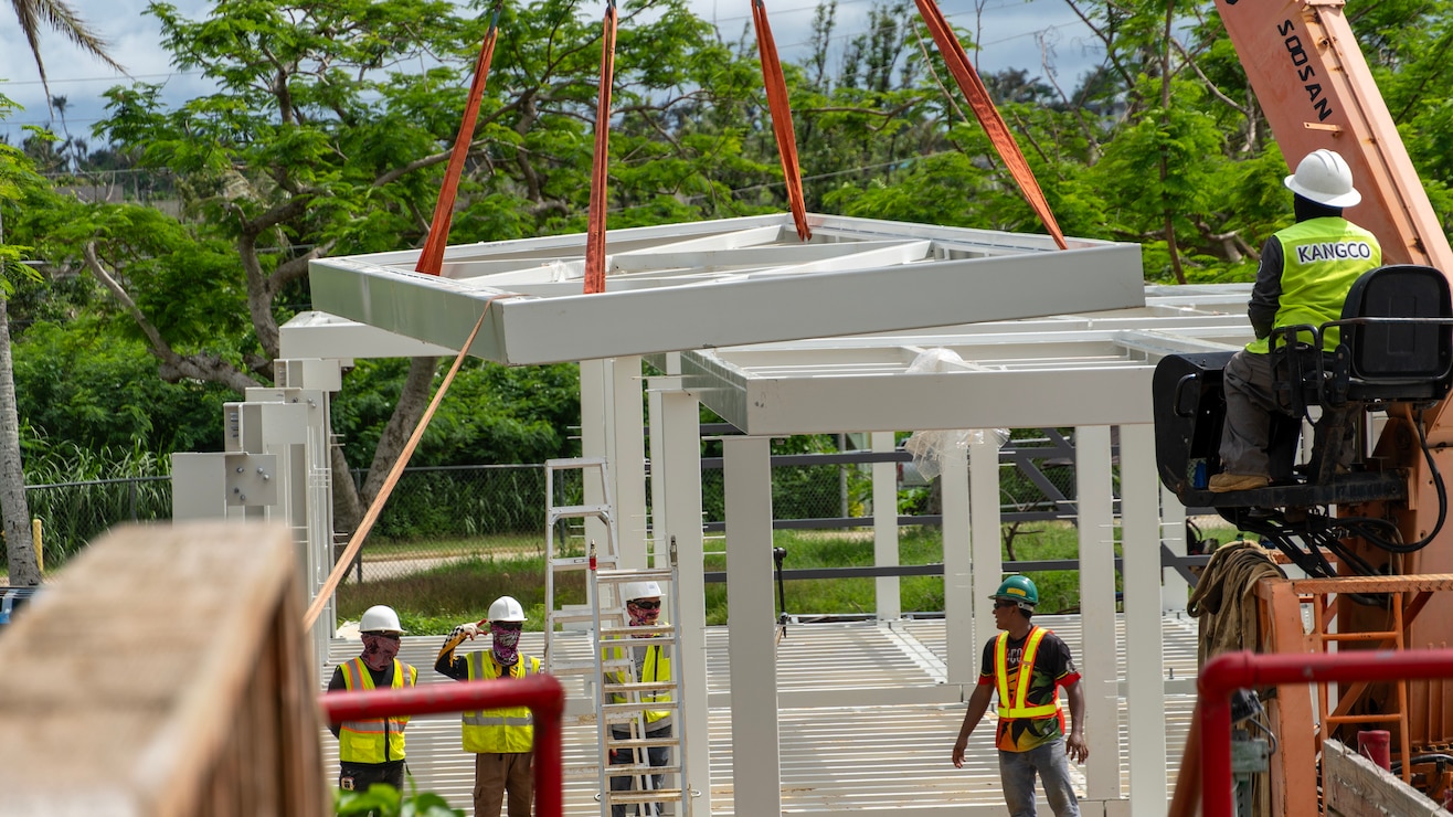 Construction workers assemble a steel building structure.