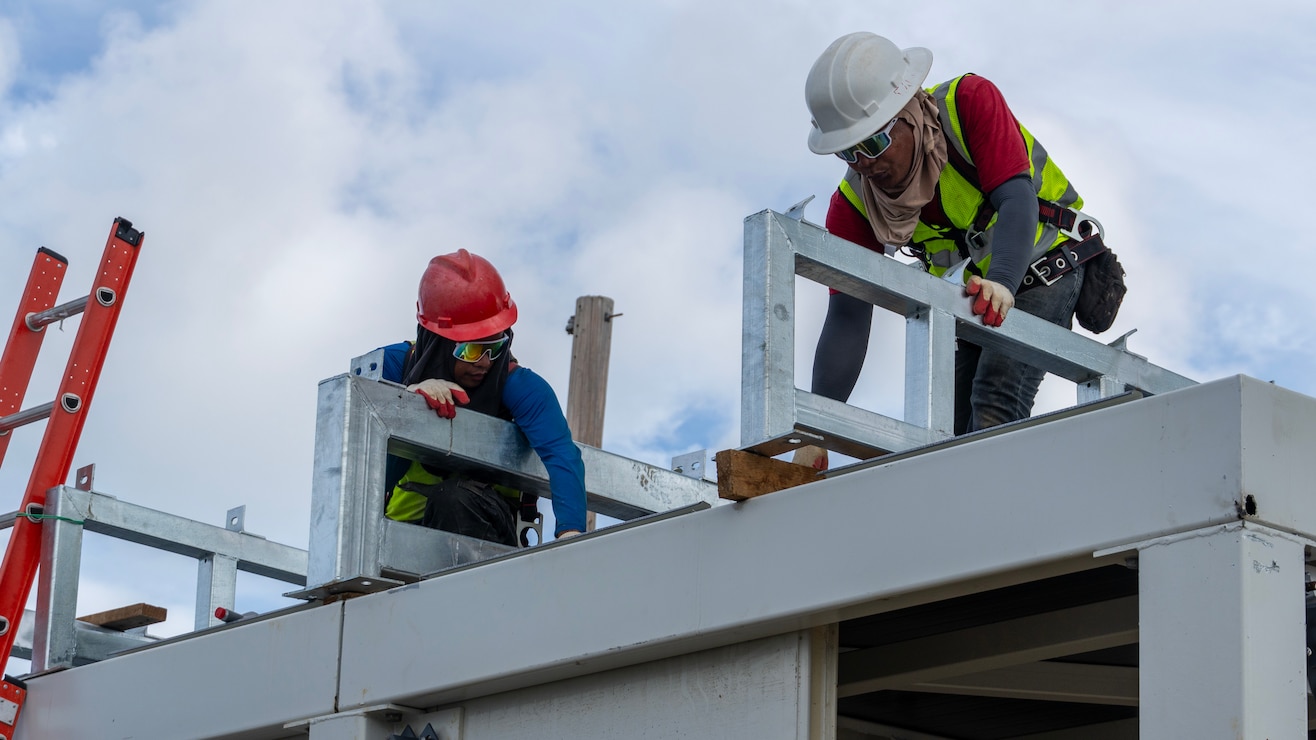 Construction workers assemble a steel building structure.
