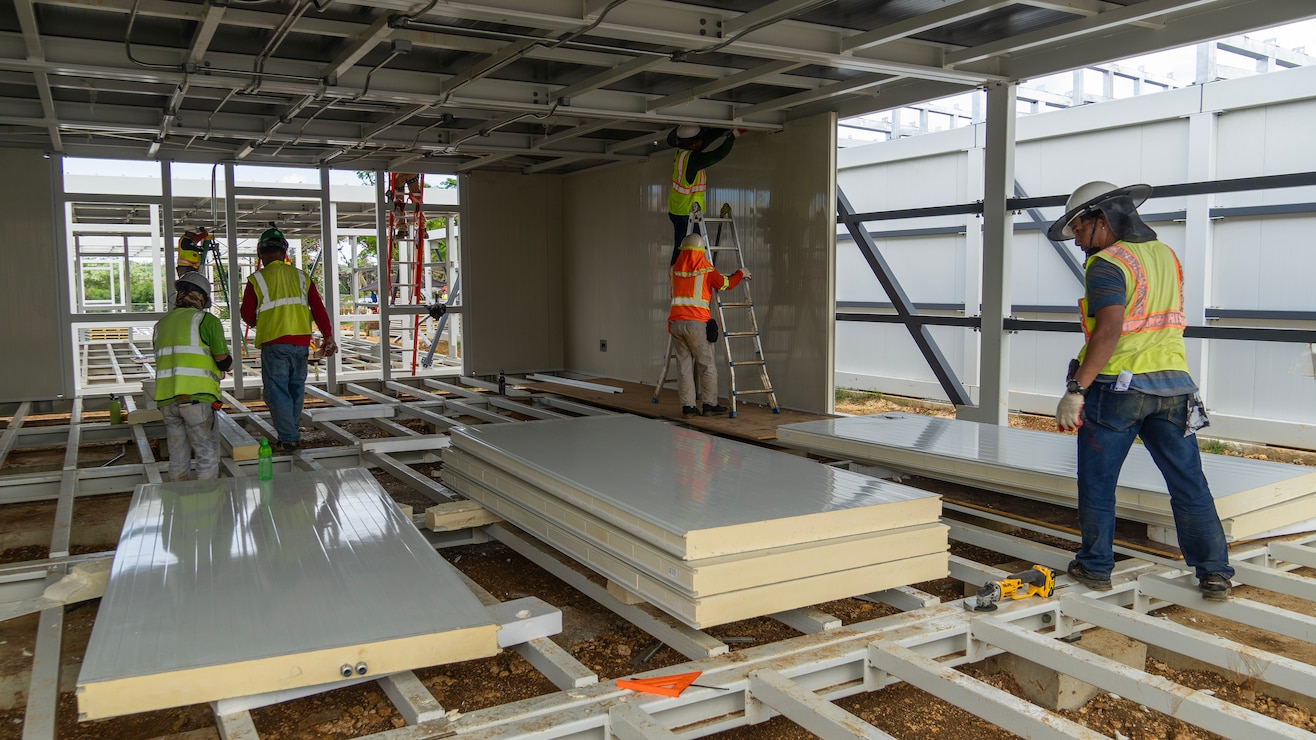 Construction workers assemble a steel building structure.