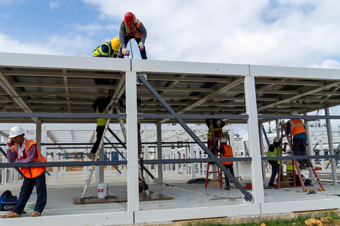 Construction workers assemble a steel building structure.