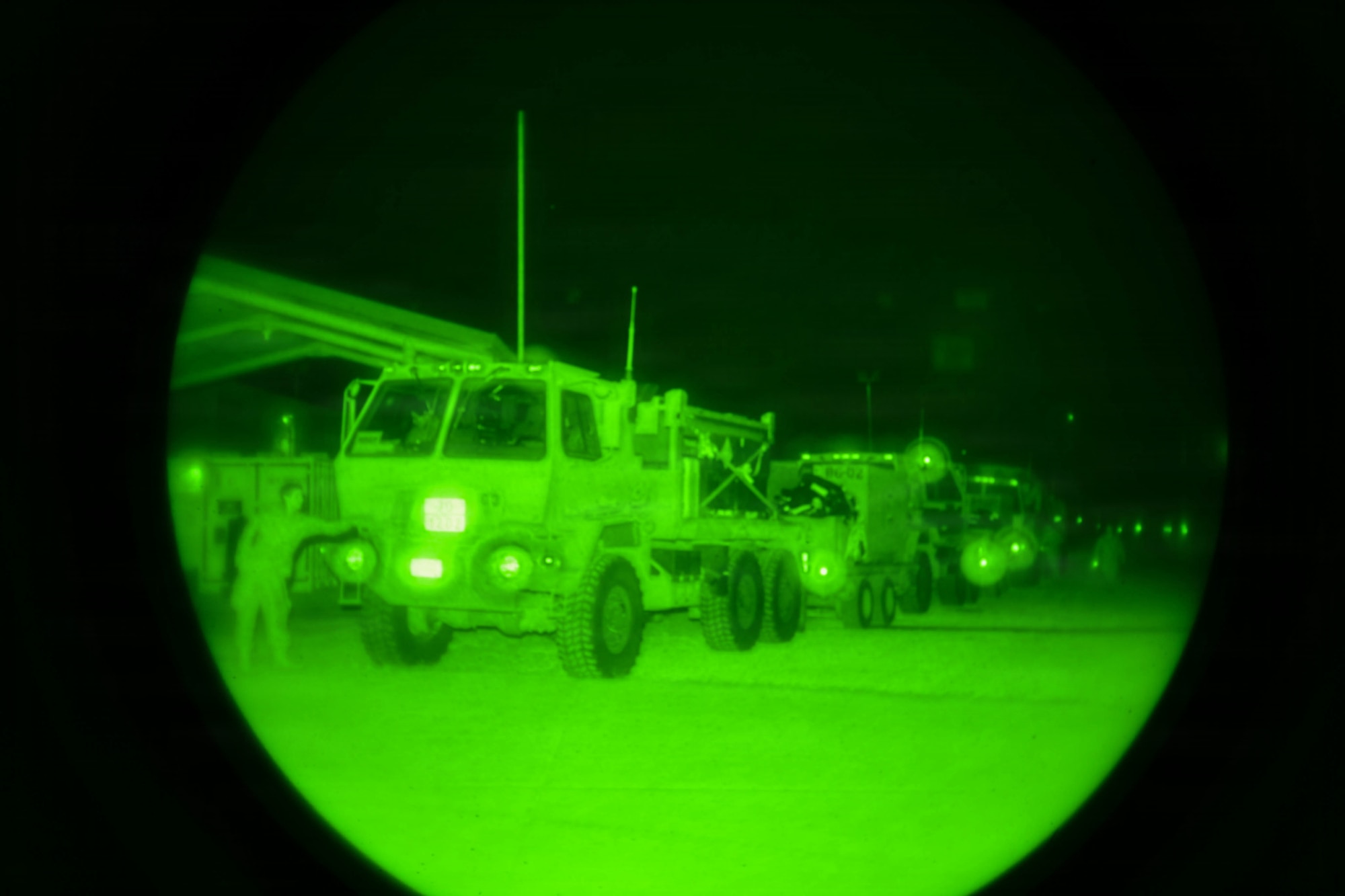 A convoy of trucks prepares to leave at night.