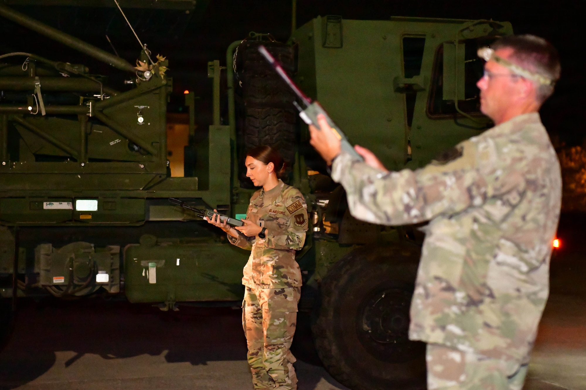 A man and woman test handheld radios at night.