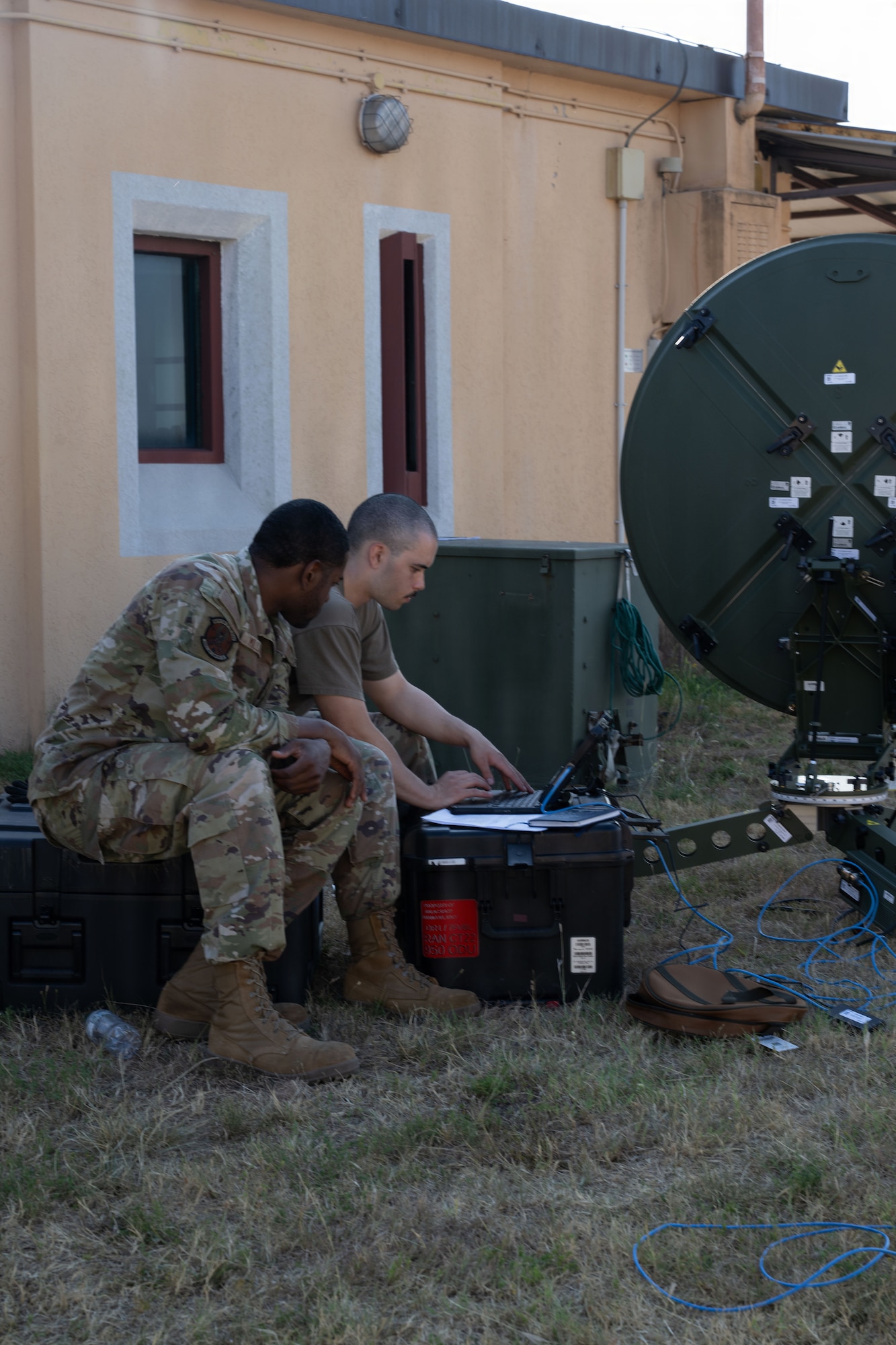 Two Airmen set up satellite communication equipment.