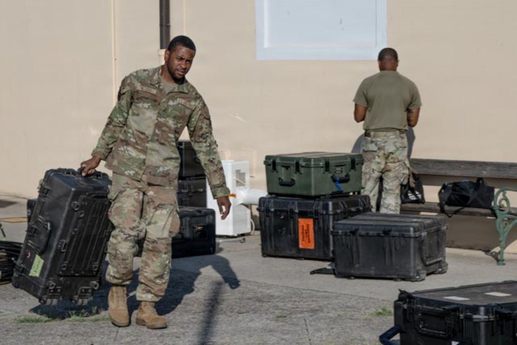 Airmen move boxes of equipment.