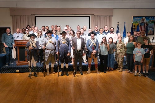Airmen, government civilians, and contractors pose with Revolutionary War reenactors at the Minuteman Commons, here, Aug 17. The 6th Middlesex Regiment Minuteman gave presentations on command and control, and intelligence, surveillance and reconnaissance operations during the Revolutionary War. The Department of the Air Force Portfolio Acquisition Executive for Command, Control, Communications and Battle Management’s Architecture System and Engineering division hosted the morale event to better understand how the past shaped modern-day operations. (Official Air Force photo by Richard Blumenstein).