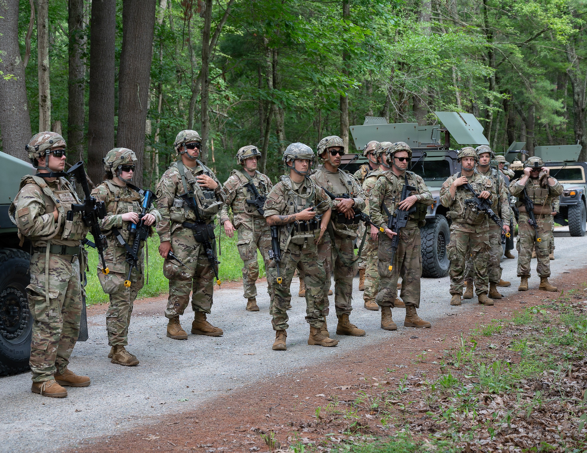 Airmen gather beside tactical vehicles.