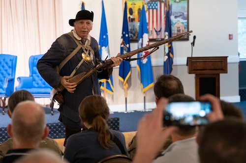 A reenactor gives a presentation to Airmen, government civilians and contractors at the Minuteman Commons, here, Aug 17. The 6th Middlesex Regiment Minuteman gave presentations on command and control, and intelligence, surveillance and reconnaissance operations during the Revolutionary War. The Department of the Air Force Portfolio Acquisition Executive for Command, Control, Communications and Battle Management’s Architecture System and Engineering division hosted the morale event to better understand how the past shaped modern-day operations. (Official Air Force photo by Richard Blumenstein).