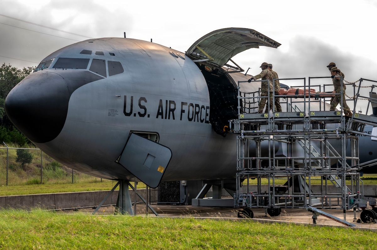 U.S. Air Force students, participating in the Aeromedical Evacuation Patient Staging Course with the 937th Training Squadron, are learning to properly carry a simulated patient off a training KC-135 Stratotanker airframe at Joint Base San Antonio-Camp Bullis, Texas, June 22, 2026. The training teaches Air Force medical personnel how to safely prepare, secure and transport patients aboard military aircraft during contingency and deployment operations. (U.S. Air Force photo by Melissa Hydrick)