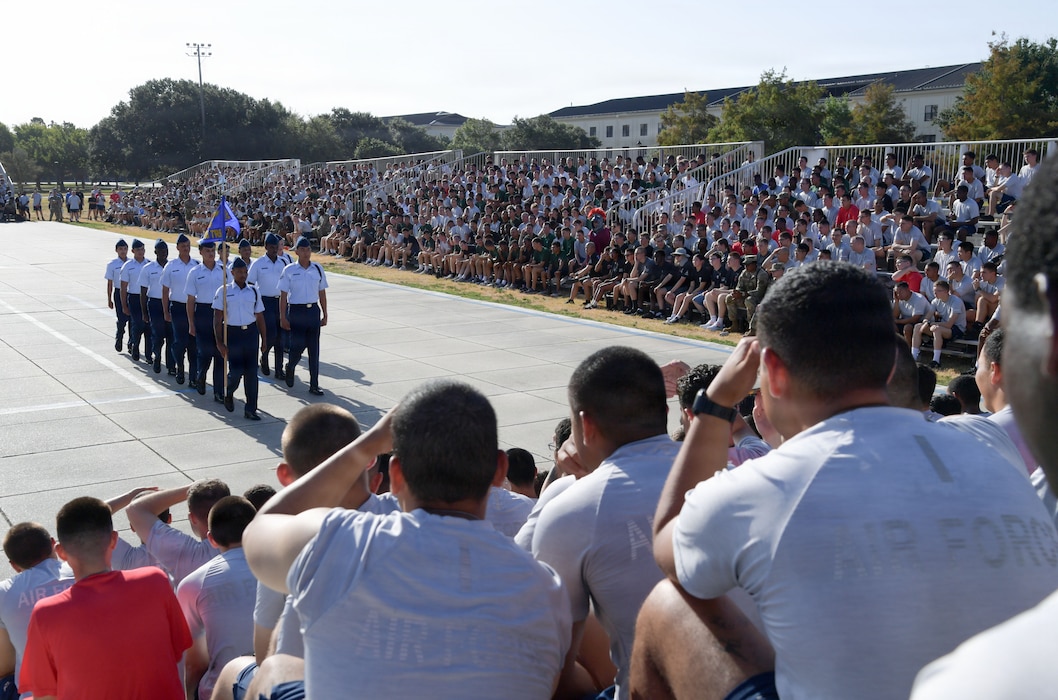 U.S. Airmen march in formation in front of an audience.