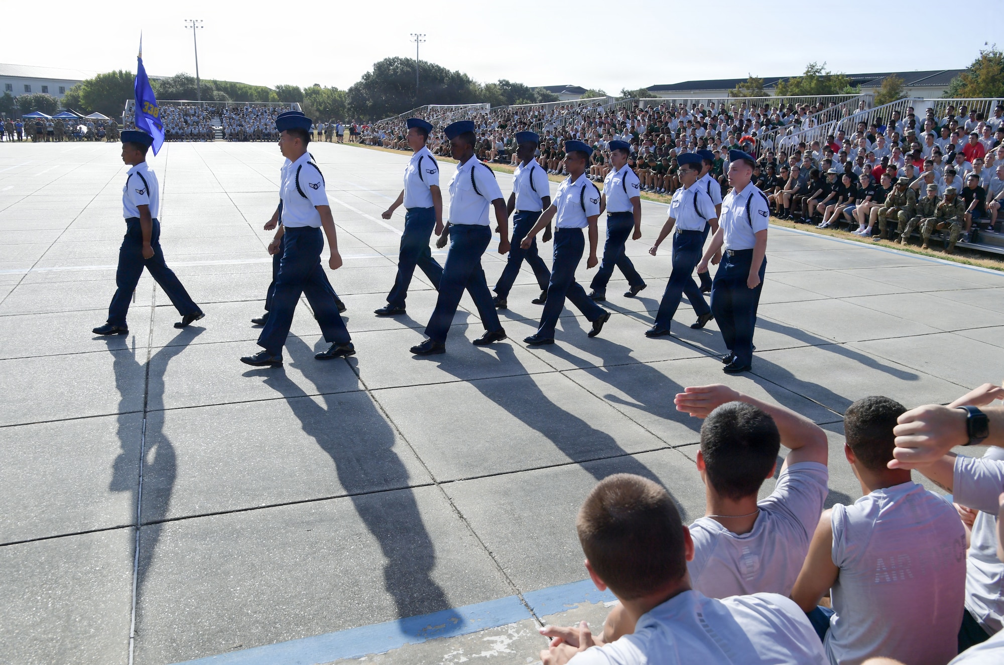 U.S. Airmen march in formation in front of an audience.