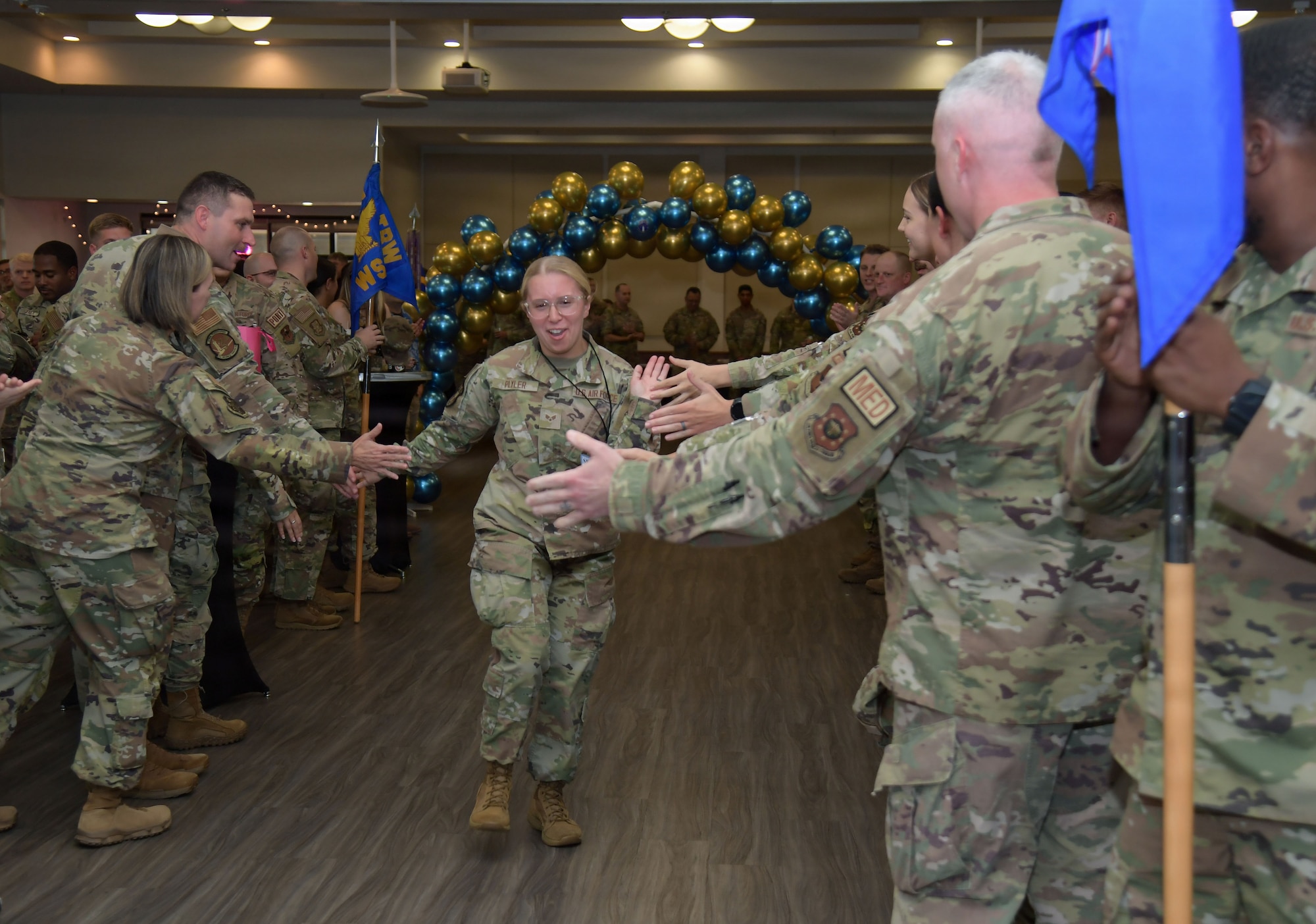 A woman in a U.S. Air Force uniform receives high-fives from other Airmen.