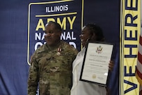 1st Class David Quinn stands alongside his spouse, Demetrie Quinn, as she displays her Certificate of Appreciation during his retirement ceremony