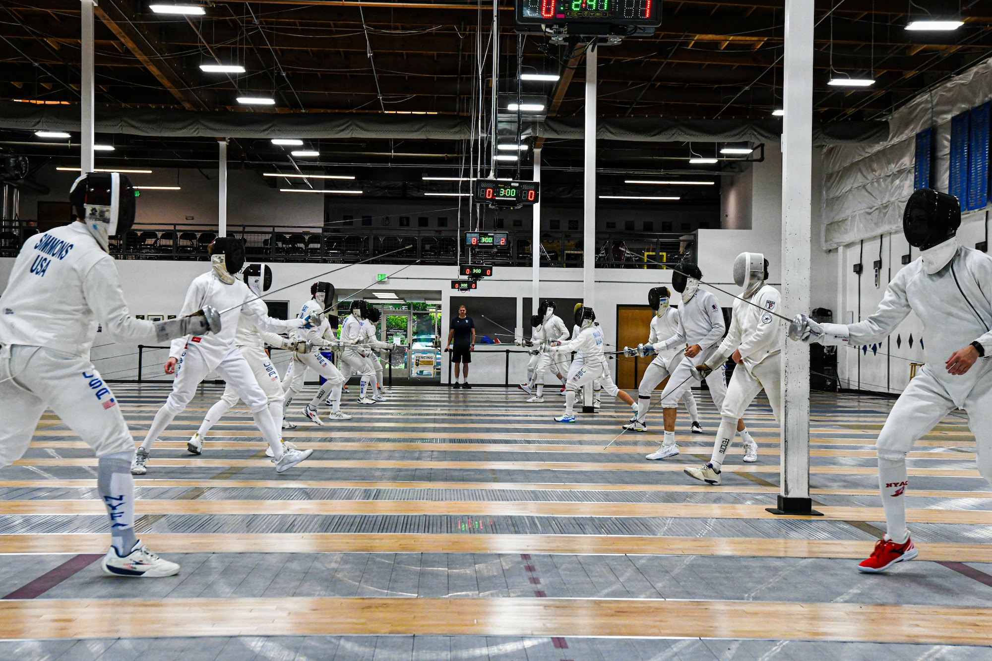 Fencers practice moves in a gym
