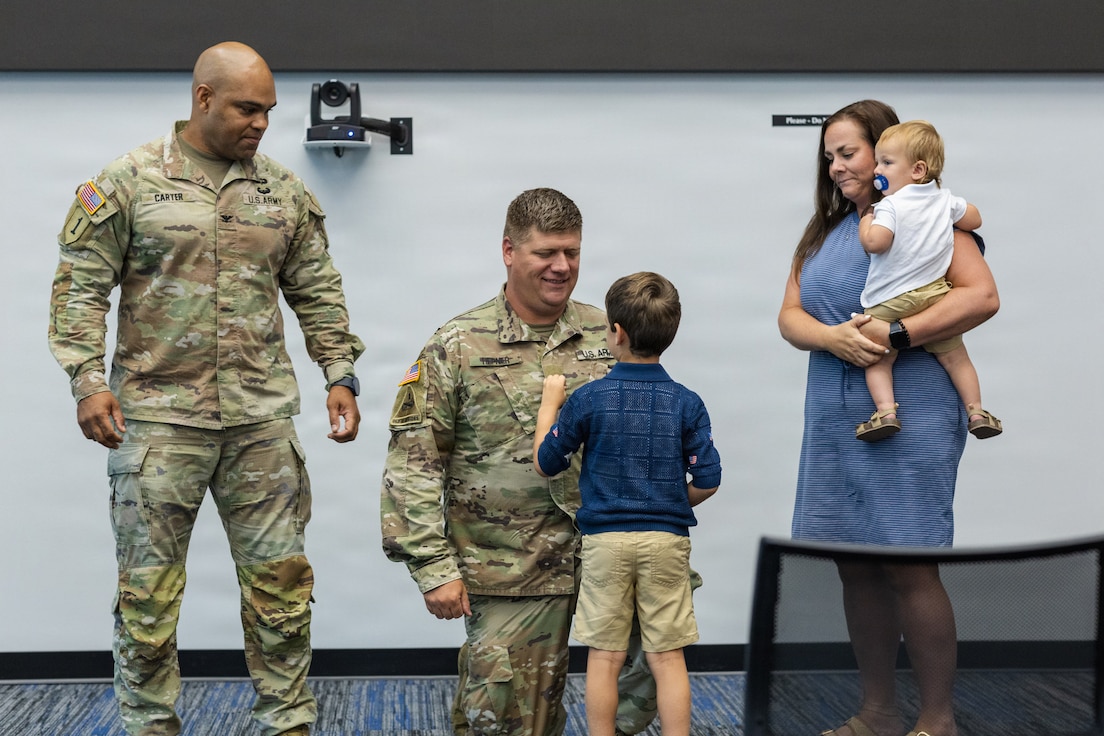 Five-year-old Arlo Hepner, the son of Illinois Army National Guard Lt. Col. Aaron A. Hepner pins his father’s new lieutenant colonel rank onto his uniform as Hepner’s wife, Jennifer, hold their other son, 1-year-old Theo