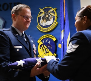 U.S. Air Force Lt. Col. Michael Rutigliano receives a folded American flag during his retirement ceremony at Francis S. Gabreski Air National Guard Base in Westhampton Beach, New York, June 6, 2026. Rutigliano retired after 30 years of dedicated service with the 102nd Rescue Squadron, assigned to the 106th Rescue Wing. (U.S. Air National Guard photo by Technical Sgt. Sean Madden)