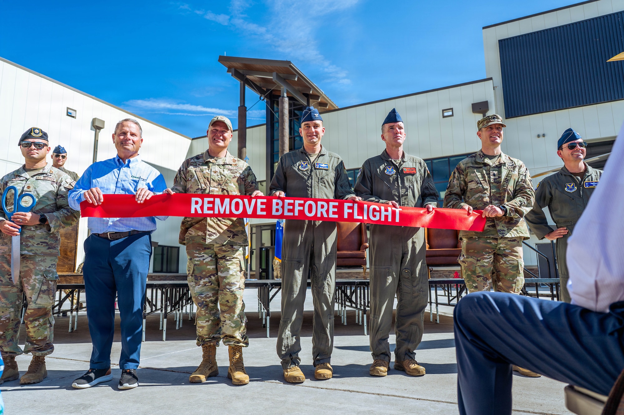 A group of leadership hold a ribbon in front of the 37th Helicopter and 90 MSOS TRF Building
