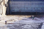 Workers with Pearl Harbor Naval Shipyard and Intermediate Maintenance Facility (PHNSY & IMF), perform a basin washdown of Dry Dock 2 immediately following dry dock dewatering at Joint Base Pearl Harbor-Hickam, July 7, 2026.