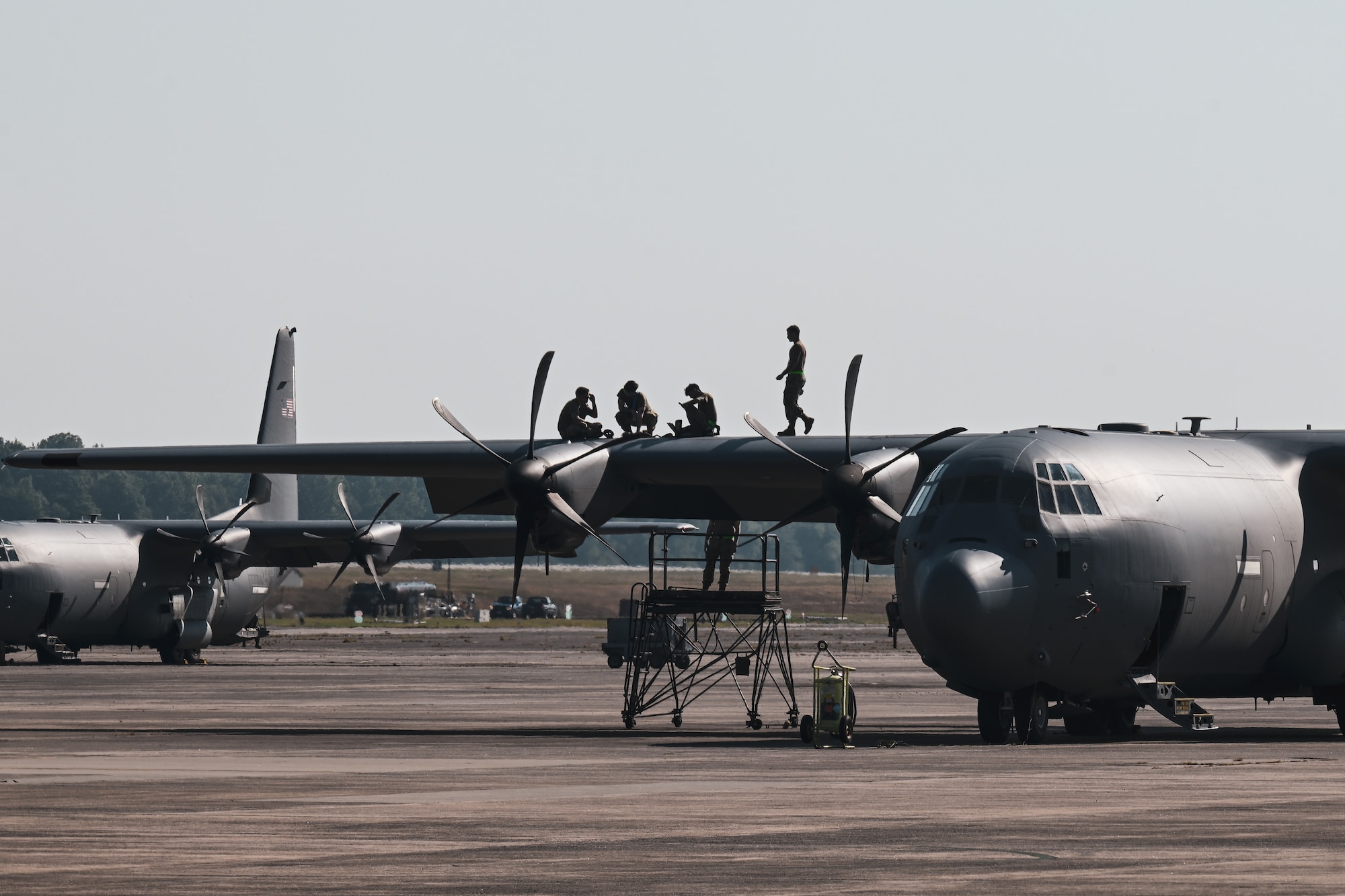 A group of Airmen work together on the wing of an aircraft.