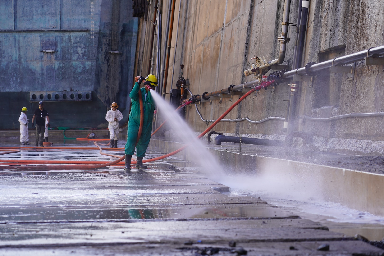 Dayton Remigio, Maintenance worker leader with Pearl Harbor Naval Shipyard and Intermediate Maintenance Facility (PHNSY & IMF), performs a high-pressure basin washdown of Dry Dock 2 immediately following dry dock dewatering at Joint Base Pearl Harbor-Hickam, July 7, 2026.