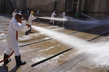 Russel Chinaka, painter helper, with Pearl Harbor Naval Shipyard and Intermediate Maintenance Facility (PHNSY & IMF), performs a high-pressure basin washdown of Dry Dock 2 immediately following dry dock dewatering at Joint Base Pearl Harbor-Hickam, July 7, 2026.