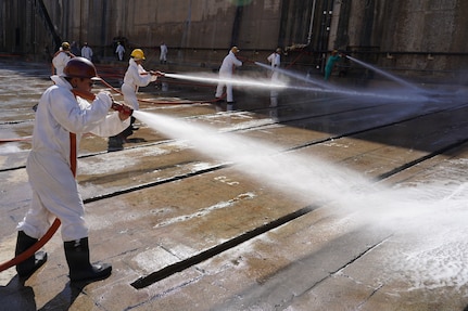Russel Chinaka, painter helper, with Pearl Harbor Naval Shipyard and Intermediate Maintenance Facility (PHNSY & IMF), performs a high-pressure basin washdown of Dry Dock 2 immediately following dry dock dewatering at Joint Base Pearl Harbor-Hickam, July 7, 2026.