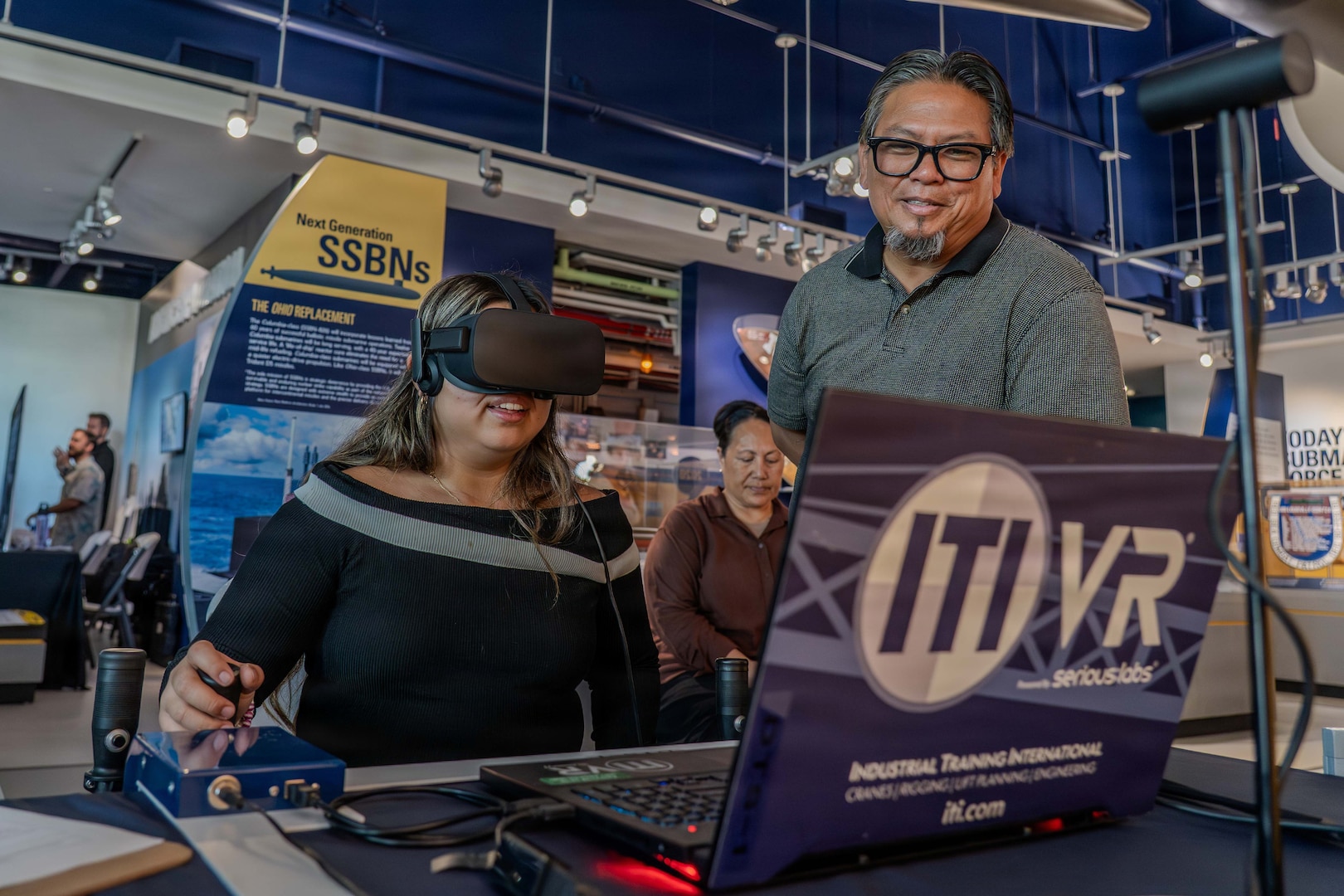 Jacob Eusebio, crane & transportation operations instructor/performance examiner with Pearl Harbor Naval Shipyard and Intermediate Maintenance Facility, helps a student navigate a mobile crane simulator during a community event at the Pacific Fleet Submarine Museum July 15, 2026.